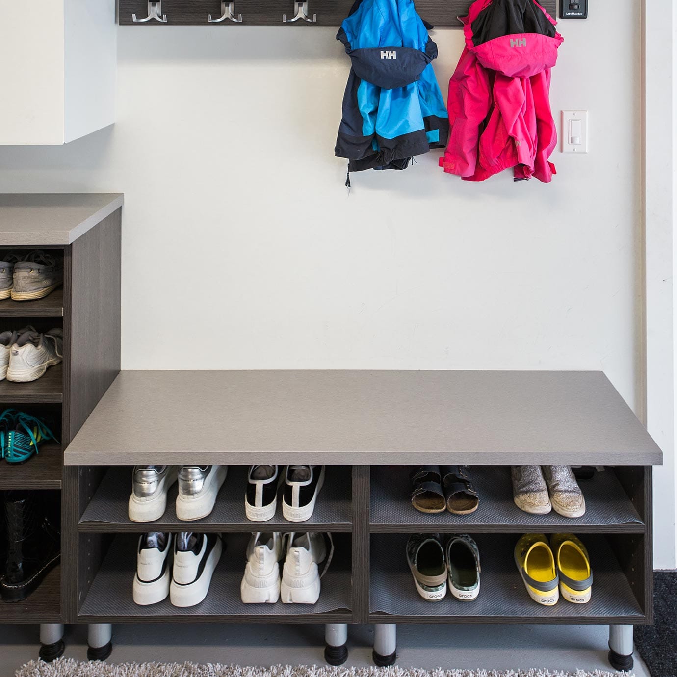 Custom shoe shelves in custom garage with shoe cabinets by California Closets